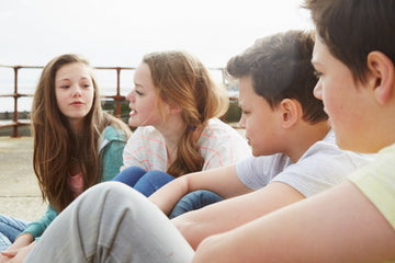 Group of pre-teens sitting outside and talking together, representing middle school friendships, social bonding, and adolescent development.