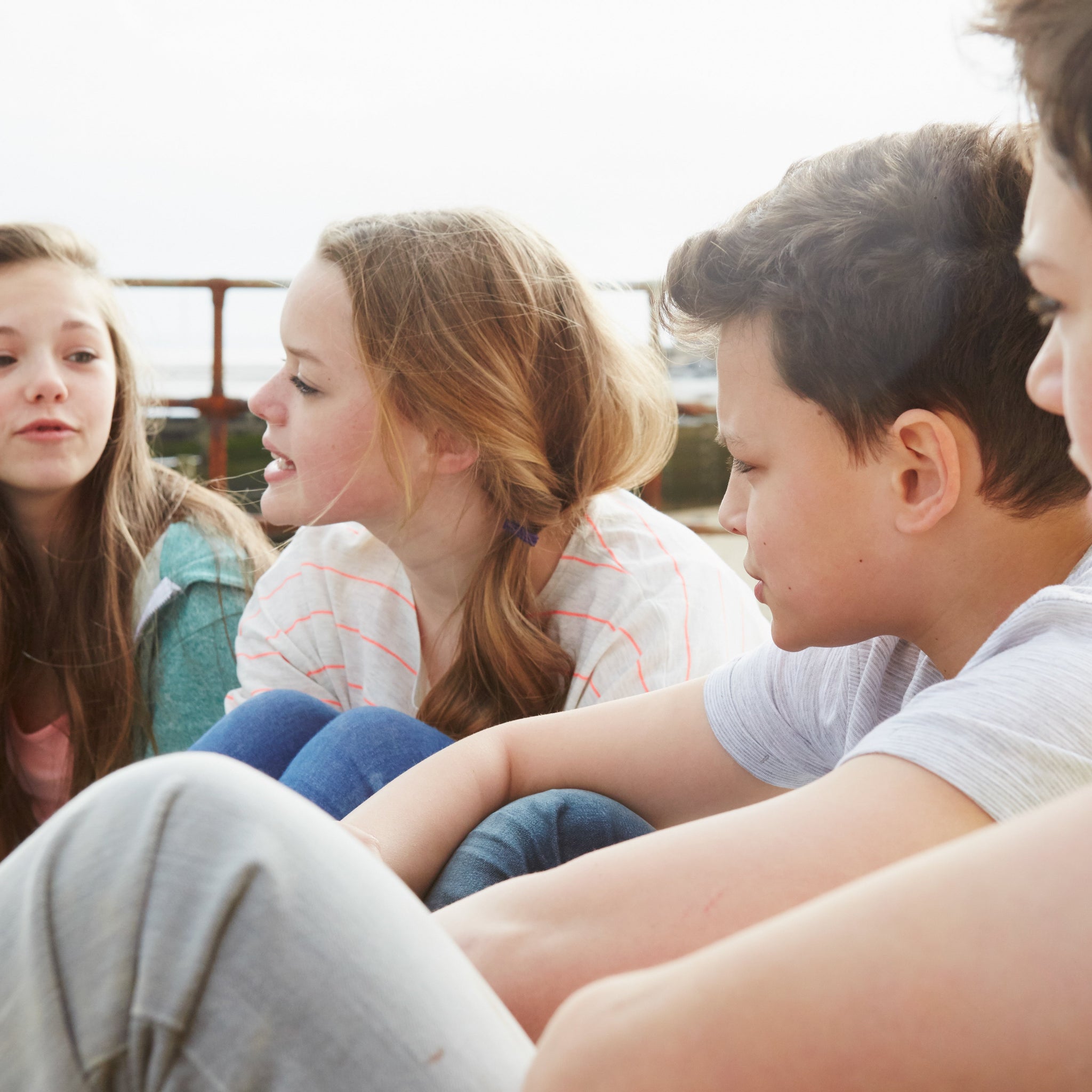 Group of pre-teens sitting outside and talking together, representing middle school friendships, social bonding, and adolescent development.